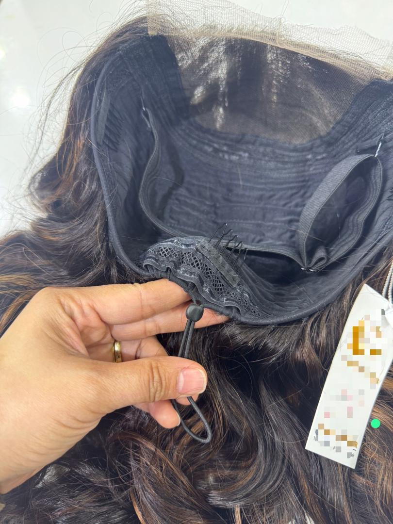 Hand holding the adjustable strap inside a wig — craftsmanship detail